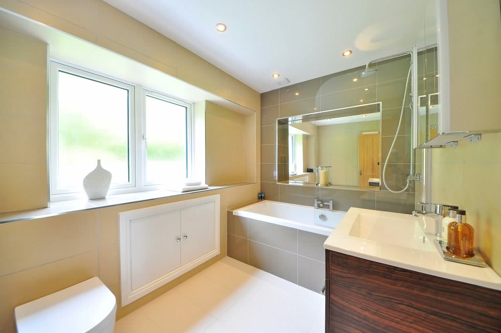 Bagno chiaro con vasca, doccia in vetro e mobile in legno